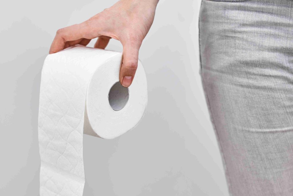 Woman holding a roll of toilet paper.