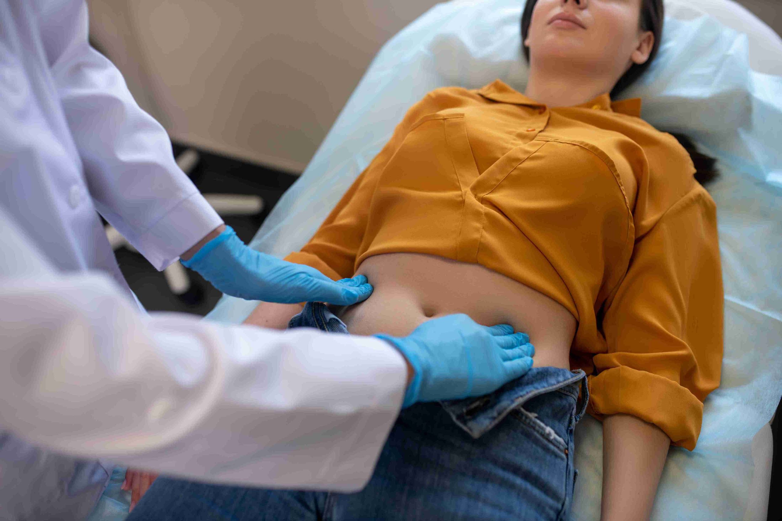 Doctor checking the stomach of a patient lying in bed.