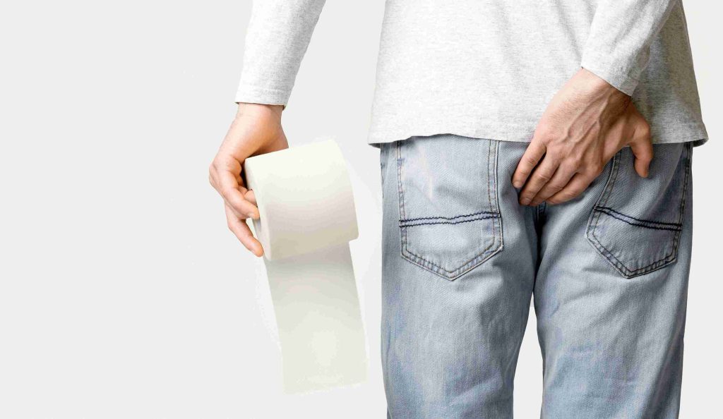 Man carrying a toilet paper and holding his butt.