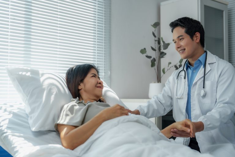 Doctor comforting patient lying in a hospital bed.