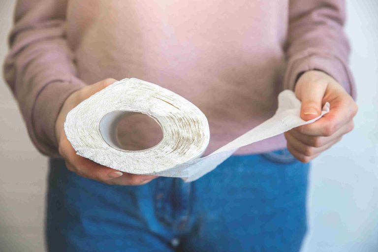 Woman holding a roll of toilet paper.