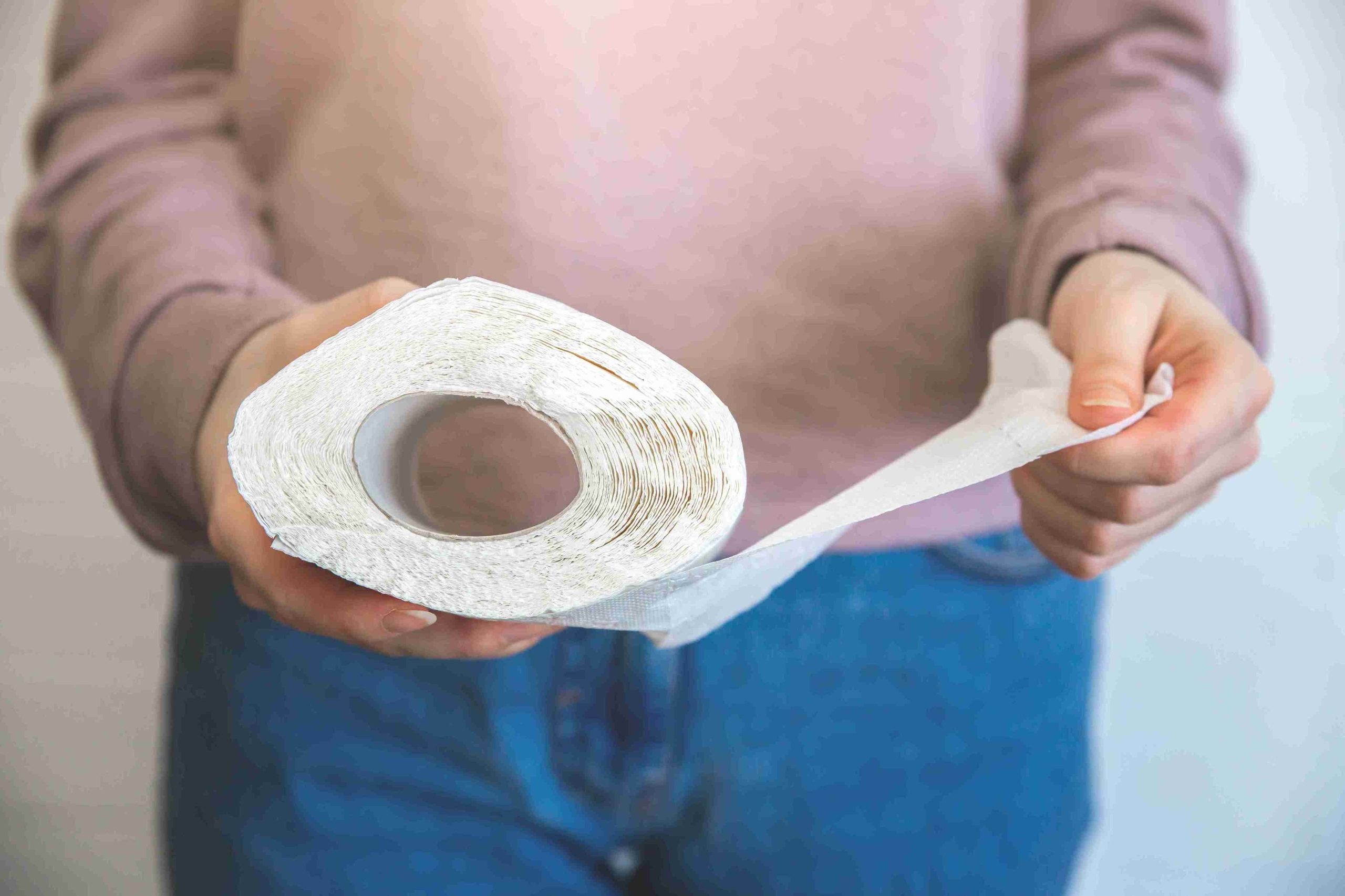 Woman holding a roll of toilet paper.