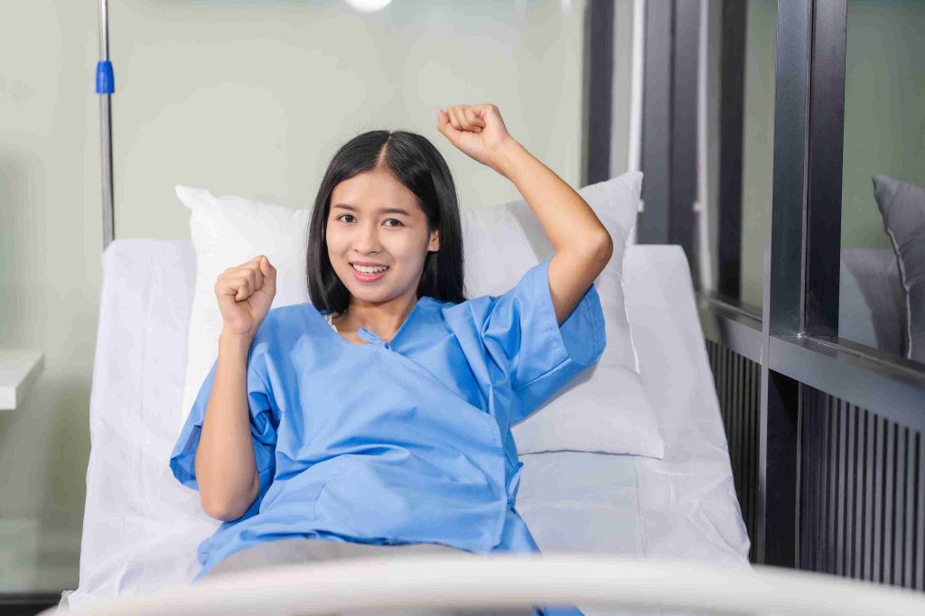 Patient smiling in hospital bed after surgery.