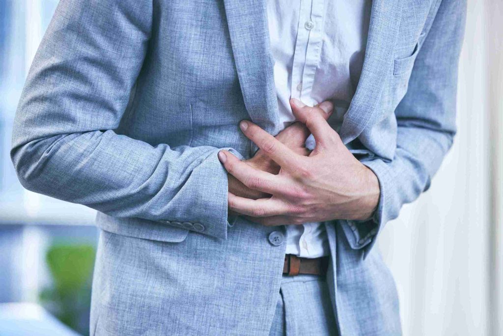 Man in business suit with hands on his stomach.