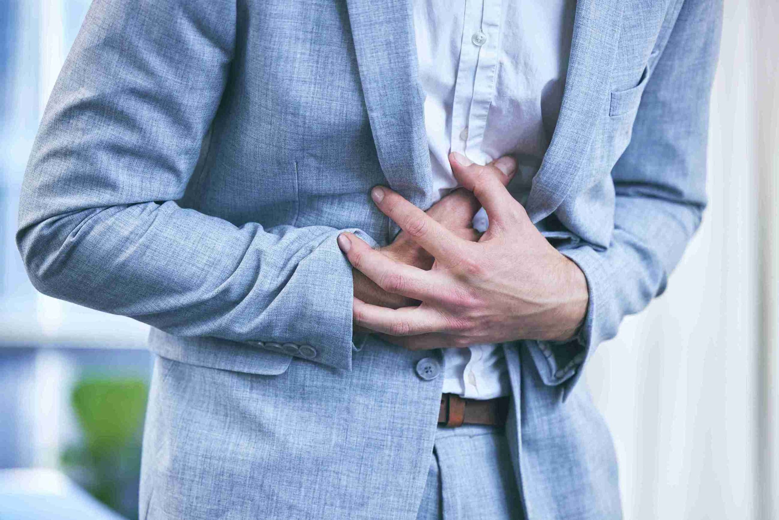 Man in business suit with hands on his stomach.
