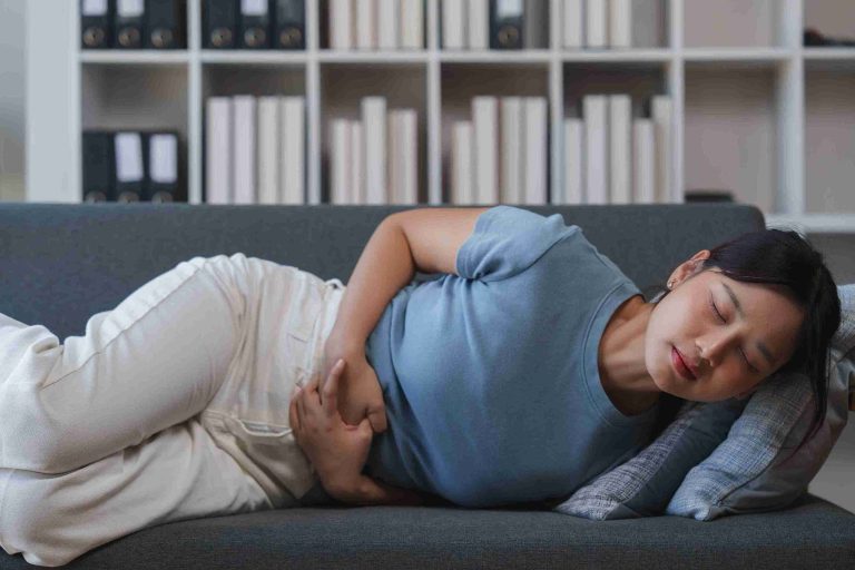 Woman with abdominal pain lying on the sofa.