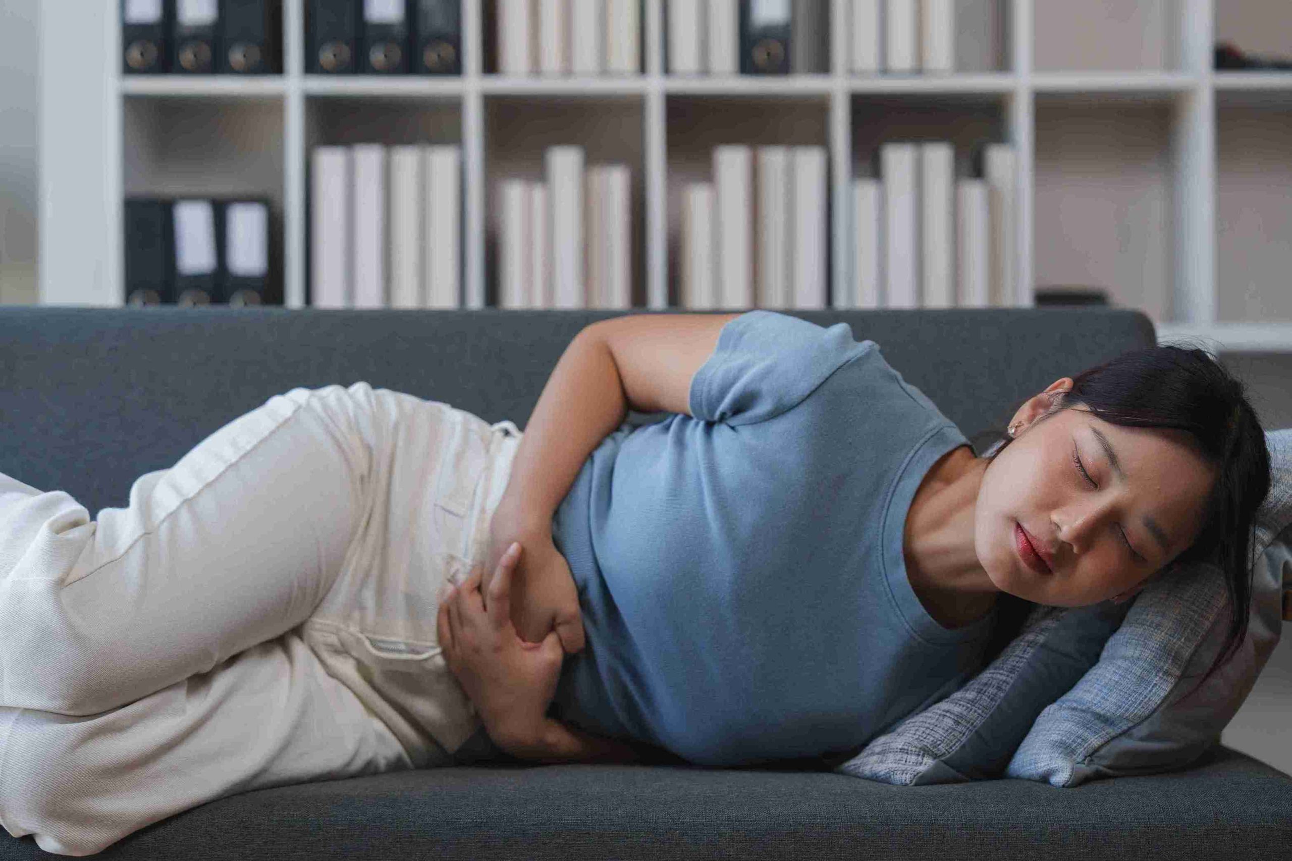 Woman with abdominal pain lying on the sofa.