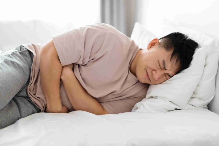 Man writhing in pain in his bed.