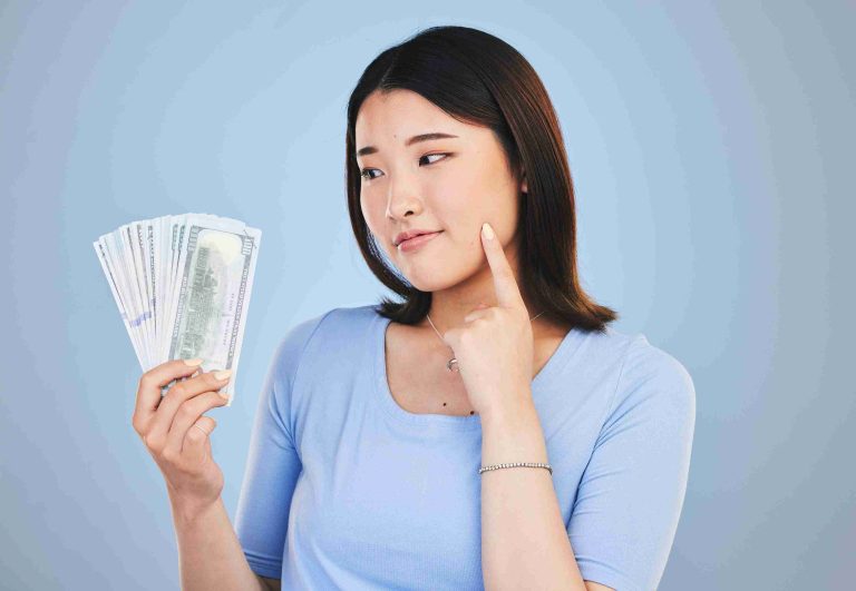 Woman holding dollar bills and thinking.
