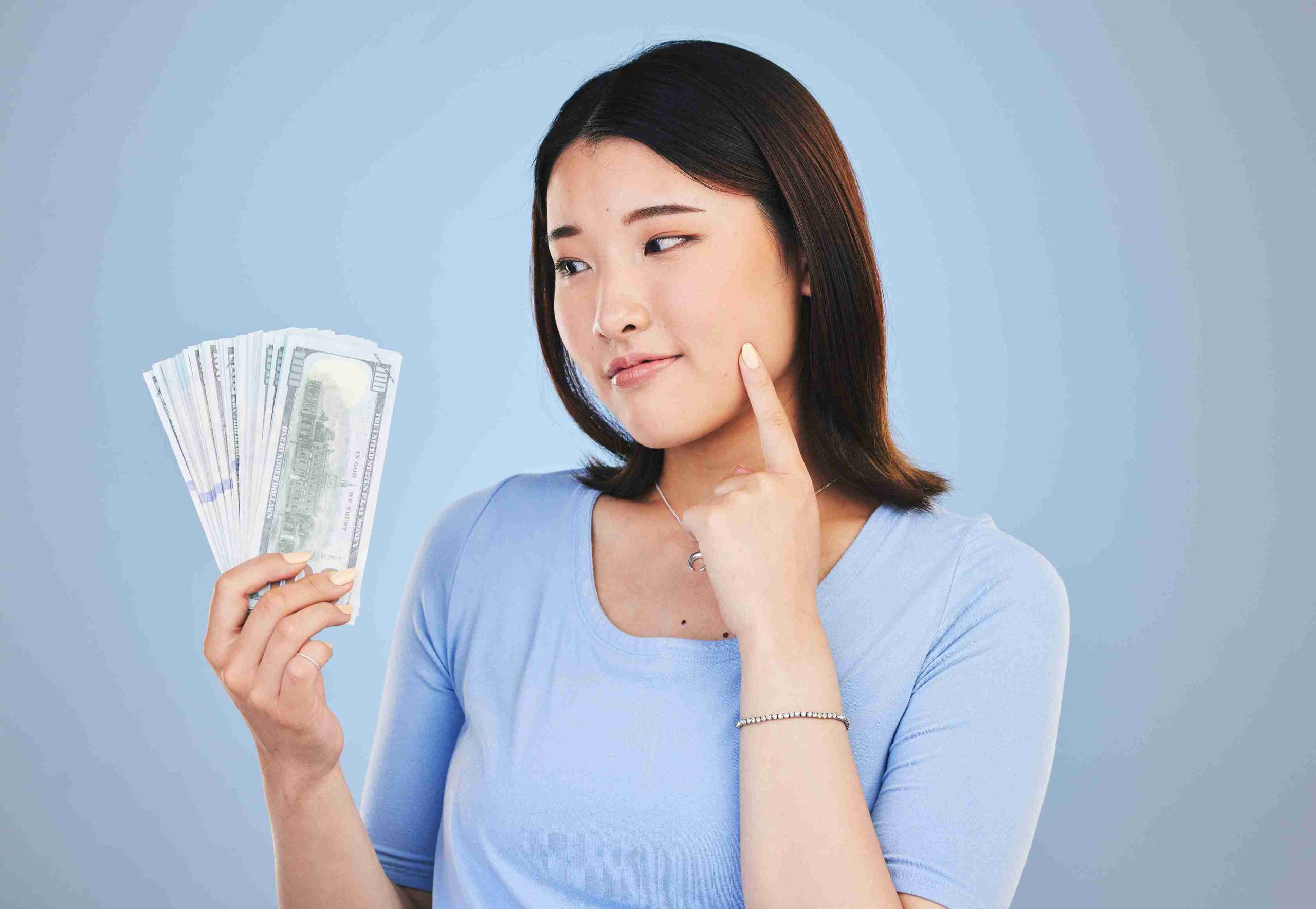 Woman holding dollar bills and thinking.