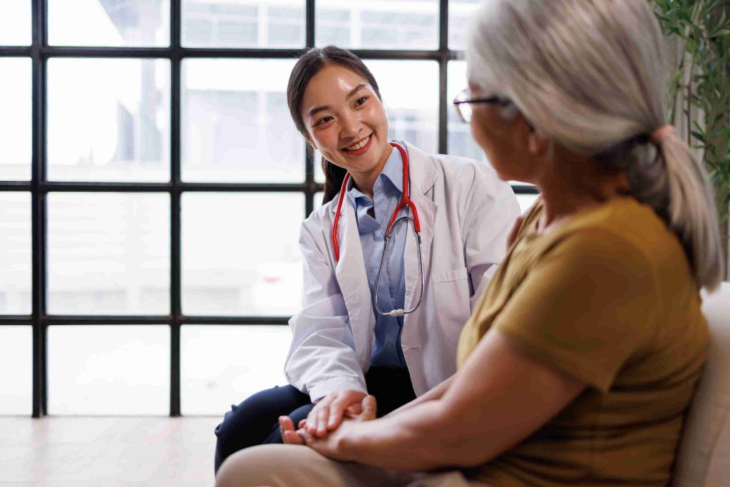 Young doctor smiling and sitting next to an elderly patient.