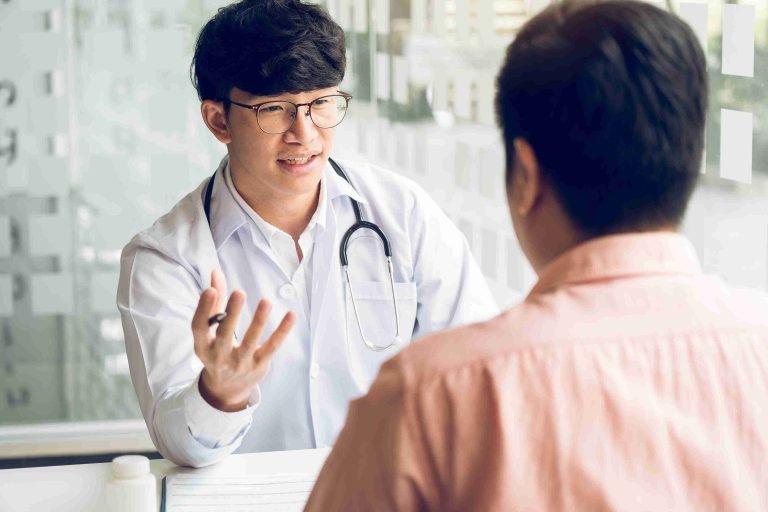 Gastroenterologist explaining 7 factors that determine when you should start colonoscopy screening using a 3D colon model.